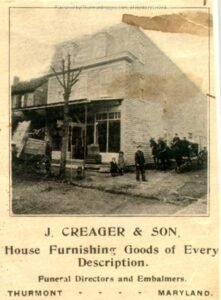 Newspaper ad showing image of row building, plus several people and a horse-drawn wagon facing the camera. Text says "J. Creager & Son, House Furnishing Goods of Every Description. Funeral directors and Embalmers. THURMONT - MARYLAND