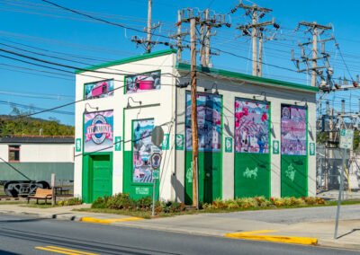 Side view of green cube building with murals