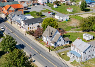 Aerial view of chapel house. White siding, red door, and a steeple in the center